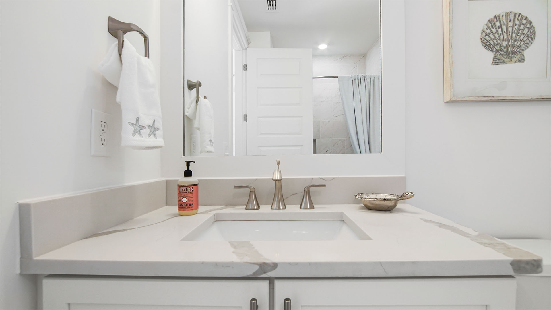 Single sink vanity with quartz countertops and white cabinetry and mirror.