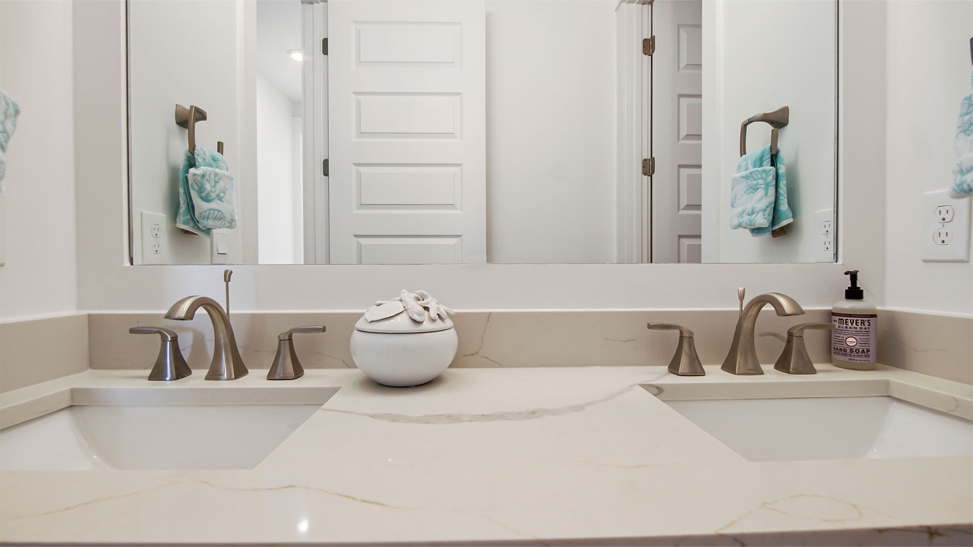 Two sink vanity with quartz countertops and a large mirror and undermount sinks.