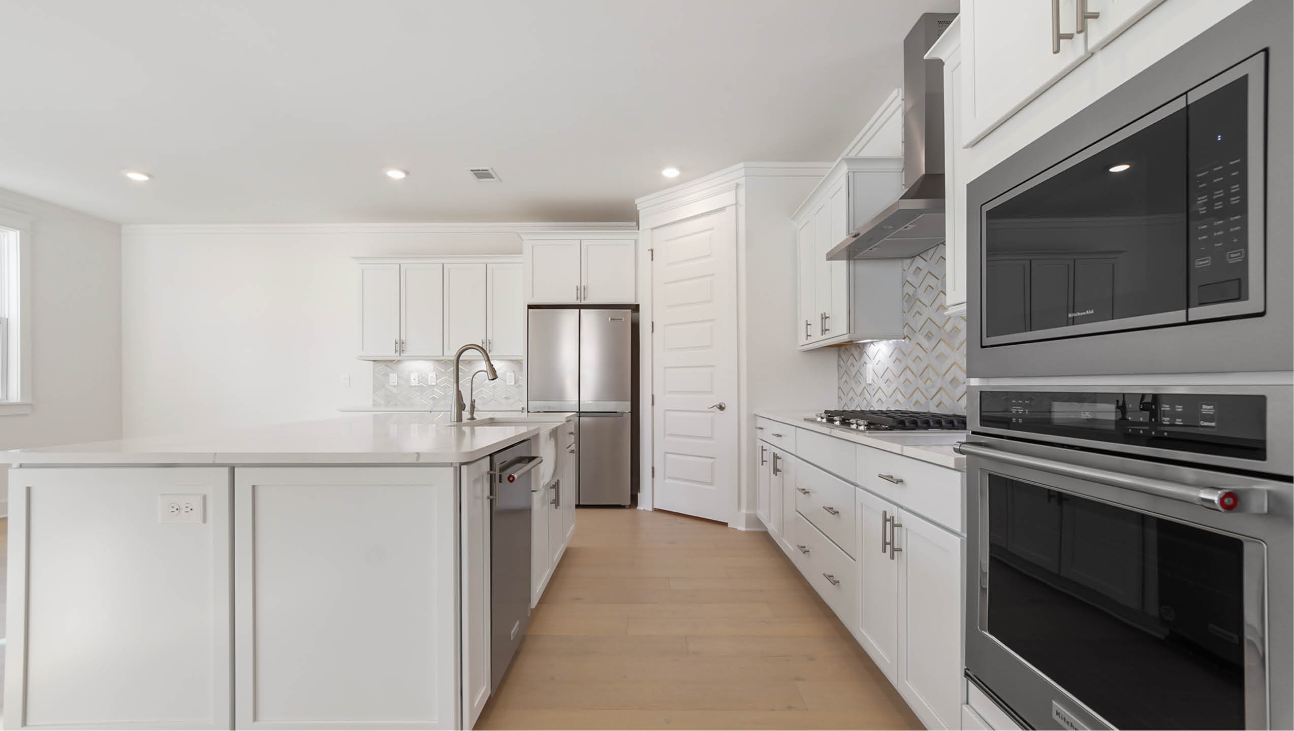 Gourmet kitchen with decorative quartz backsplash and built in wall oven