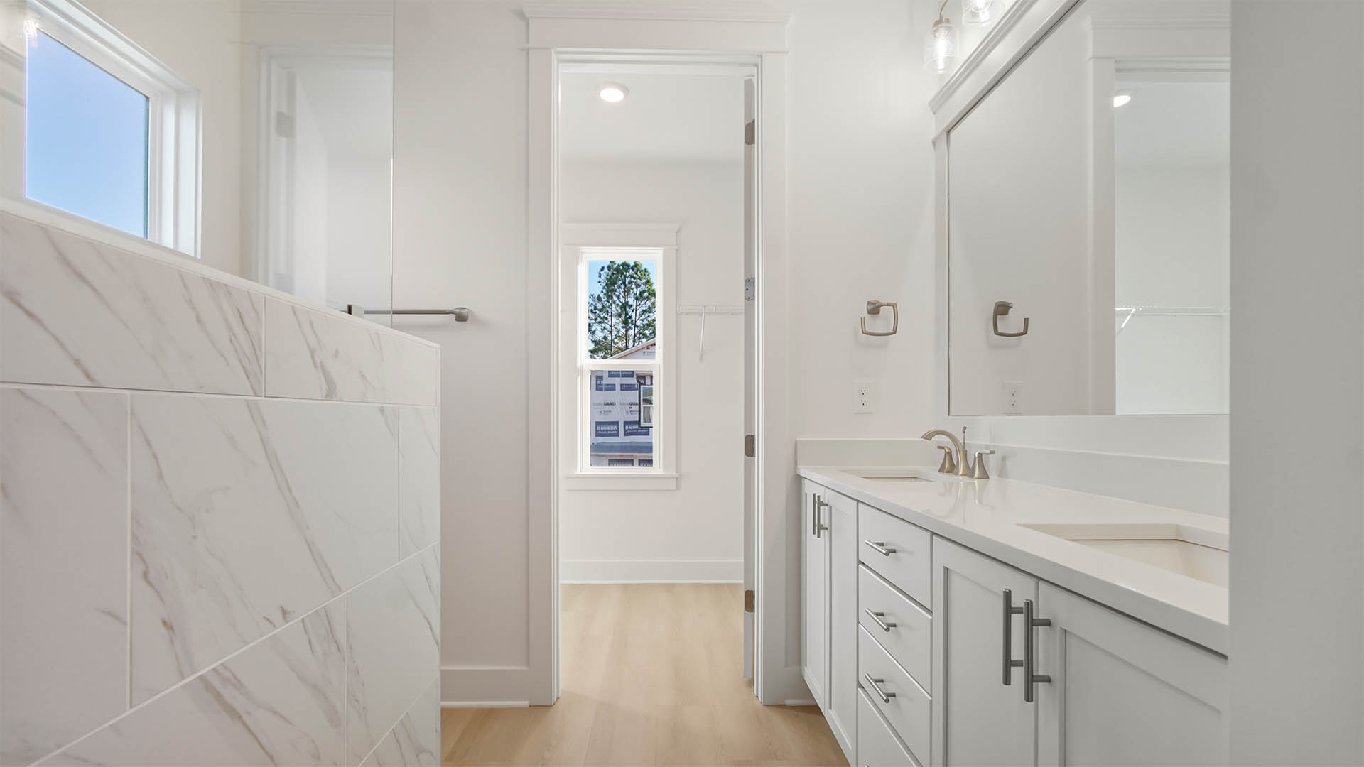 Elegant primary bathroom with dual sink vanity featuring quartz countertop and lower cabinetry