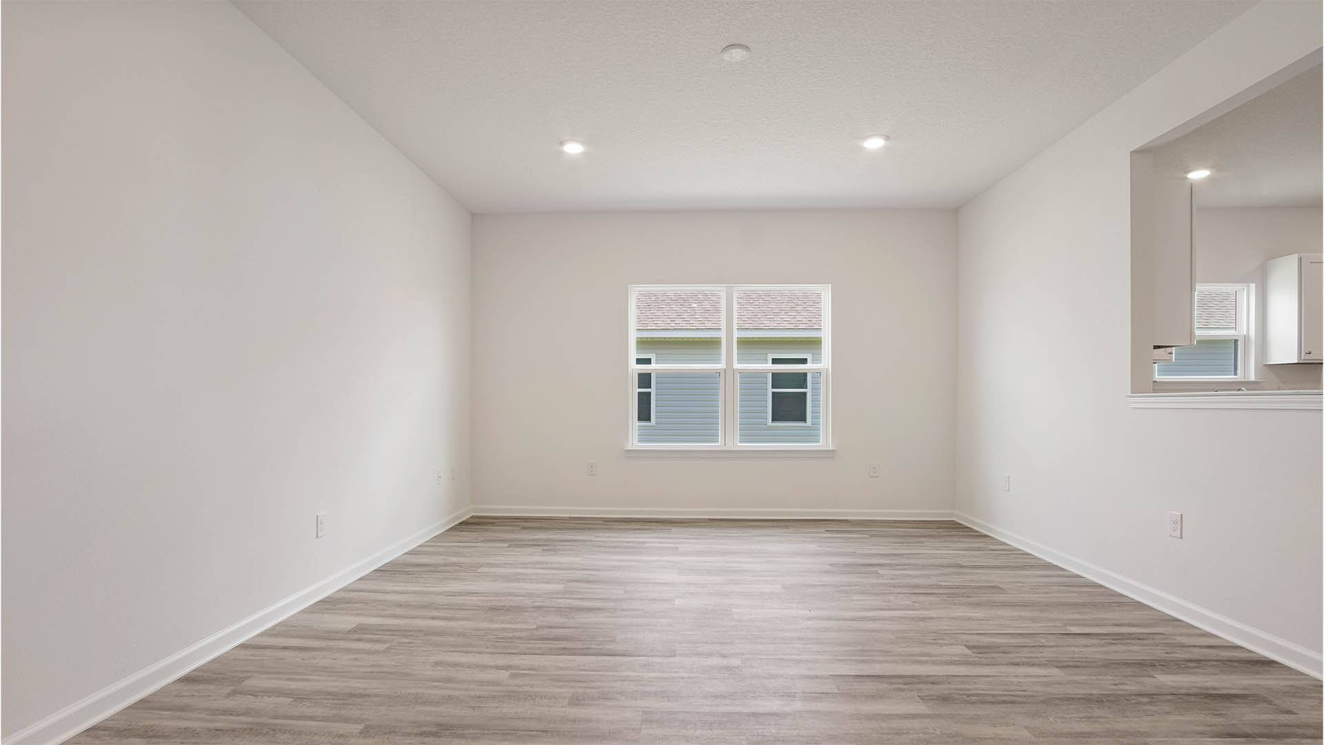 Living room with picture window and wall cutout into kitchen.