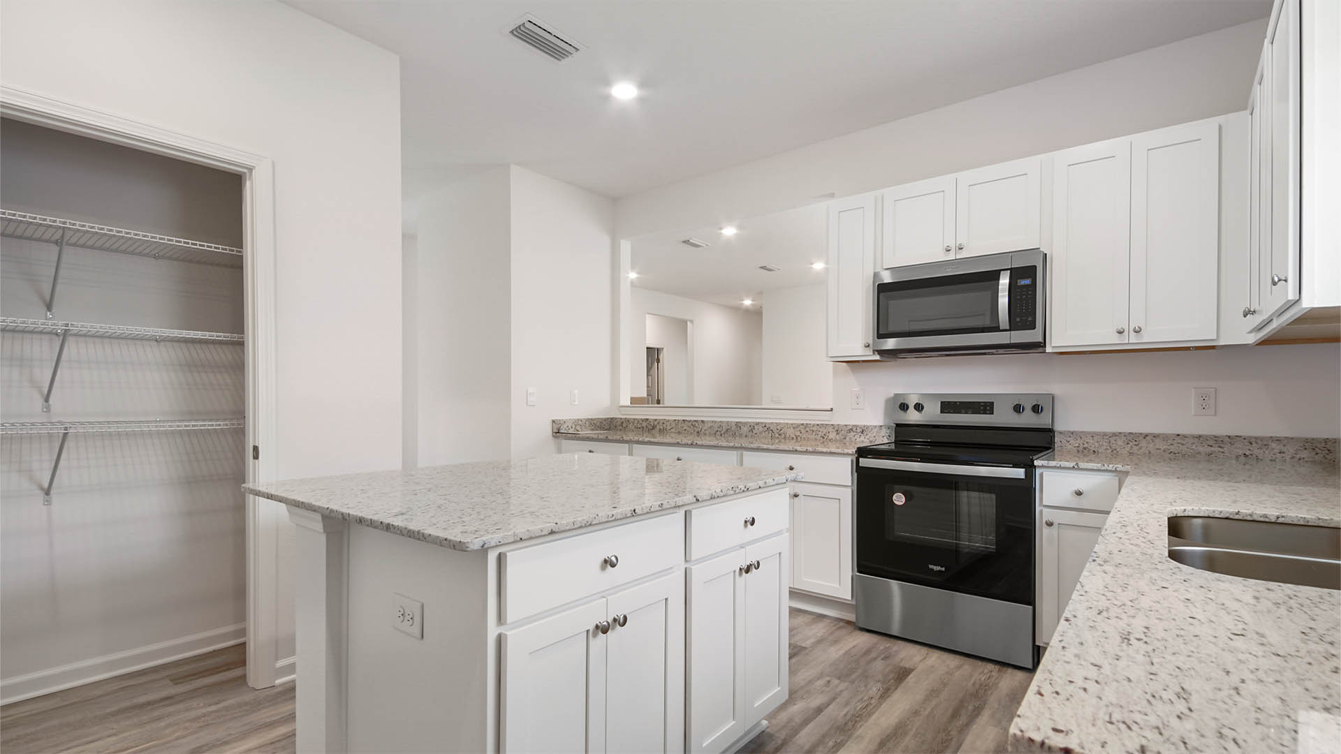 The kitchen is spacious and has stainless appliances and a pantry with ventilated shelving