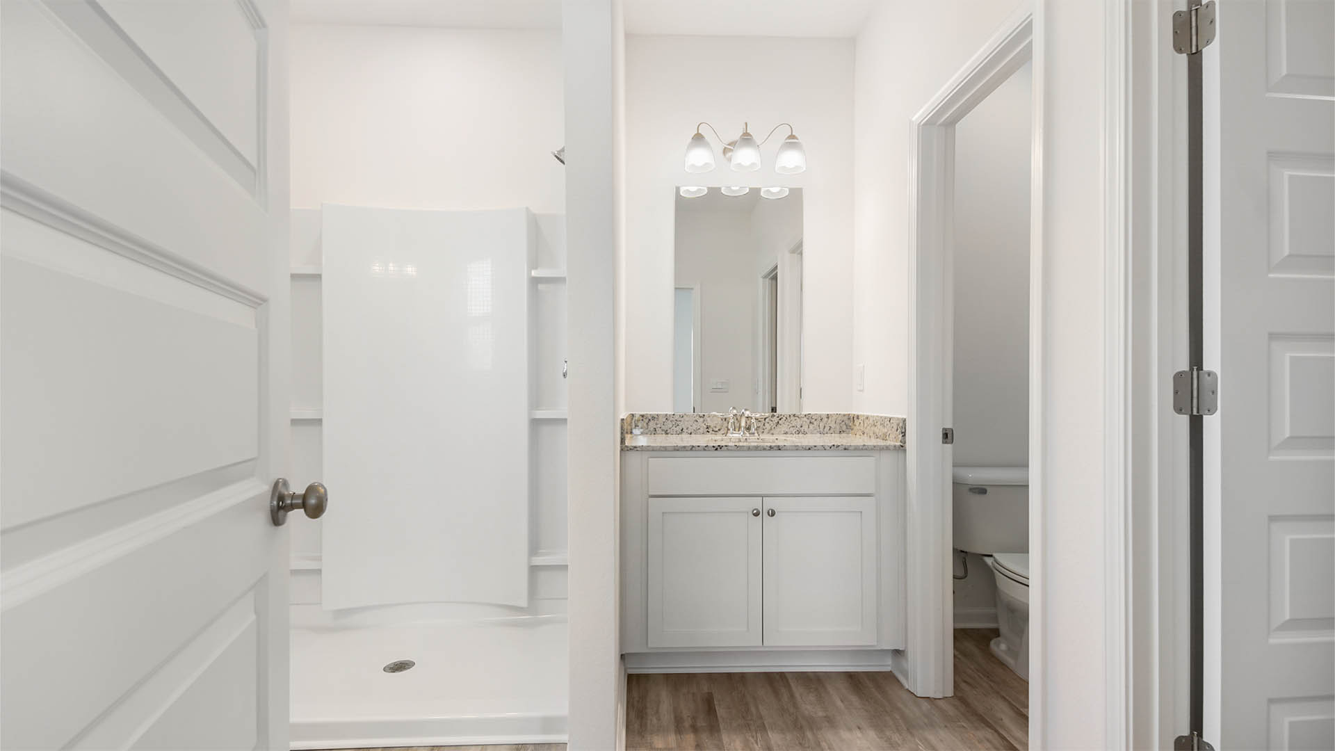 The primary bathroom has a shower and two single vanities with granite countertops and lower cabinetry for storage