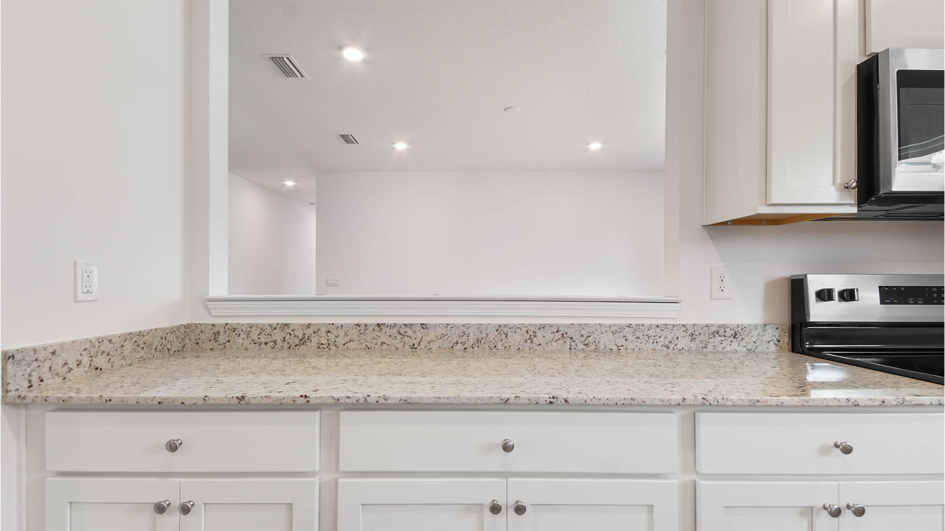 The pass through window has surrounding trim and counterspace with granite for serving