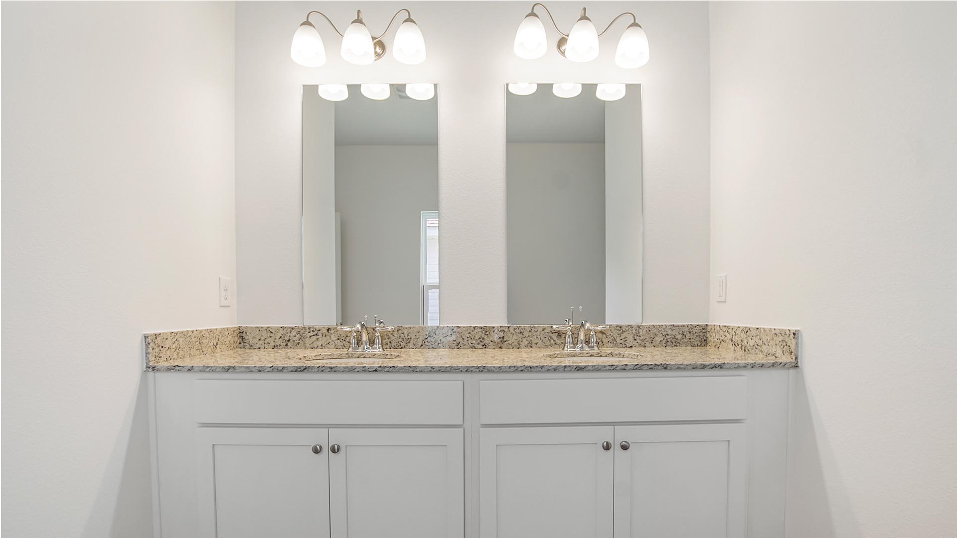 The vanity features dual sinks and lower white cabinetry as well as granite countertops