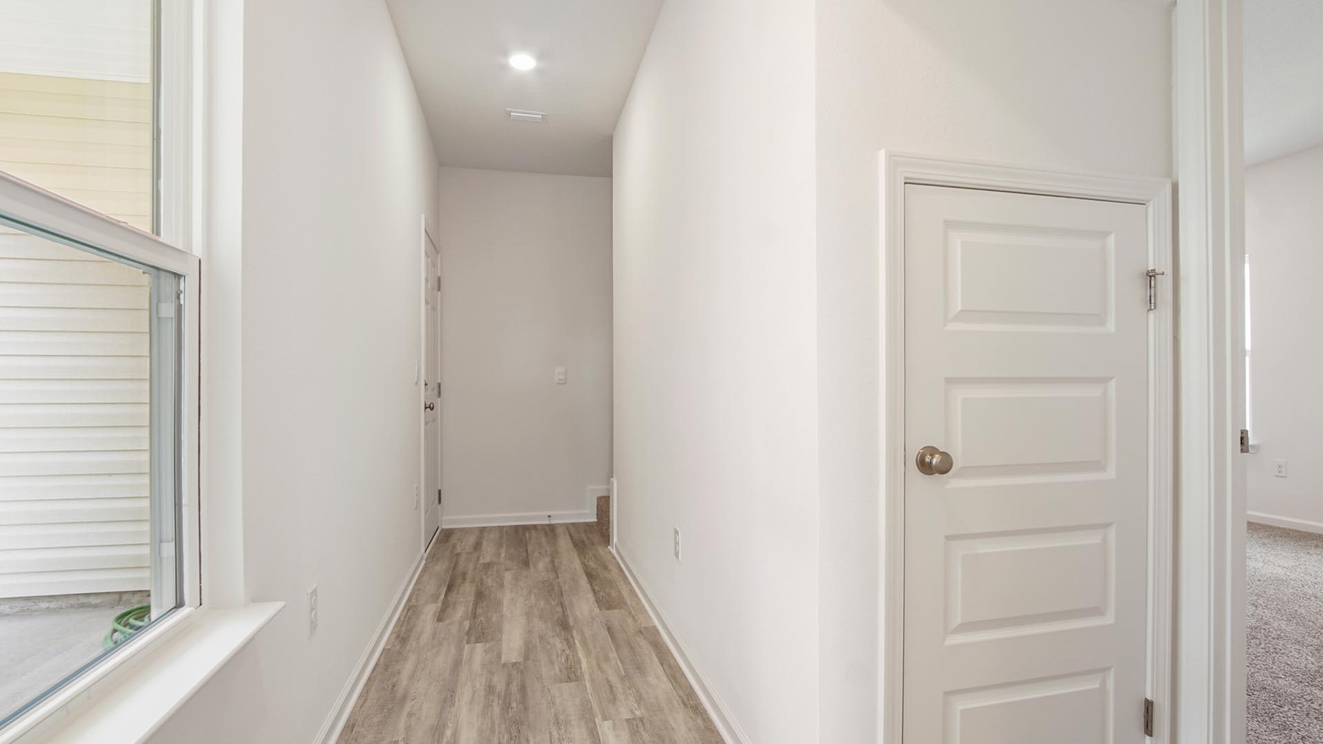 The Cary has a downstairs primary bedroom located off the hall leading to the rear entry garage and second level