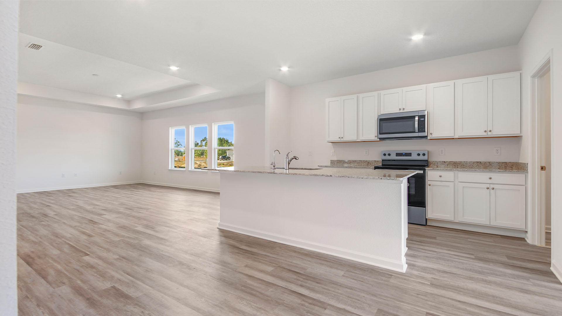 Open concept design with living area featuring trey ceilings