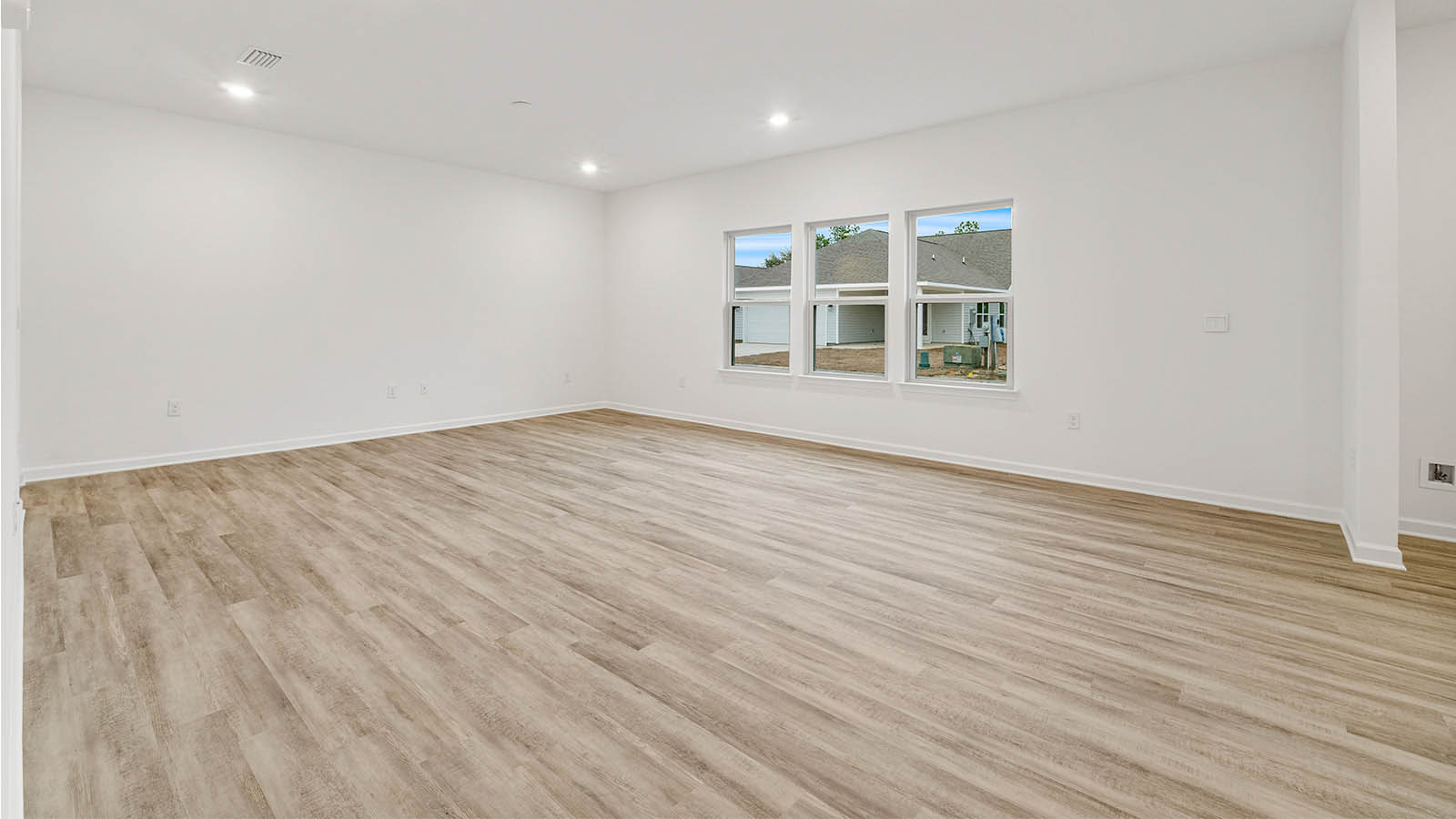 The spacious living area is adorned with expansive windows and features EVP flooring