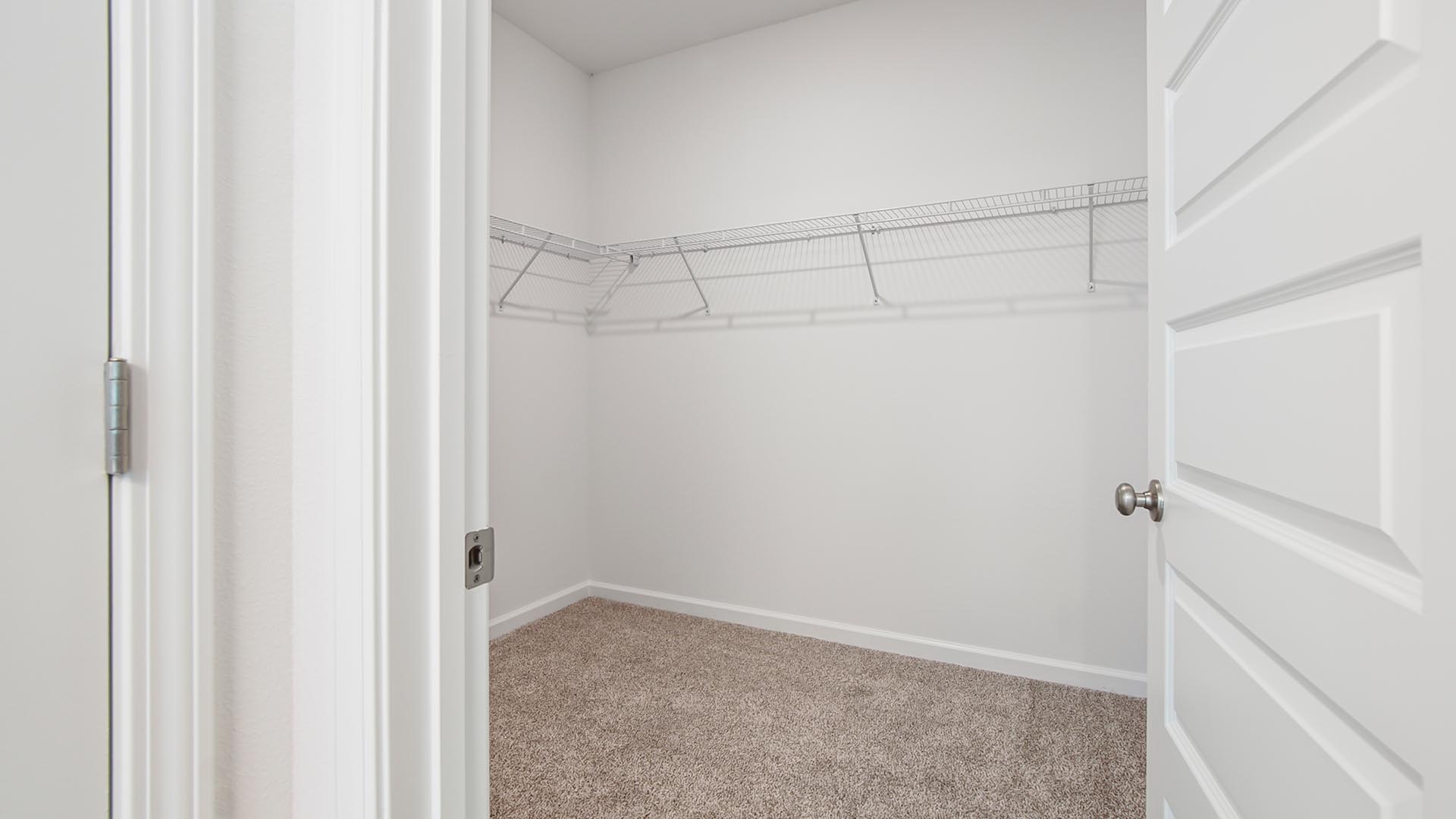 The walk in closet has upper ventilated shelving