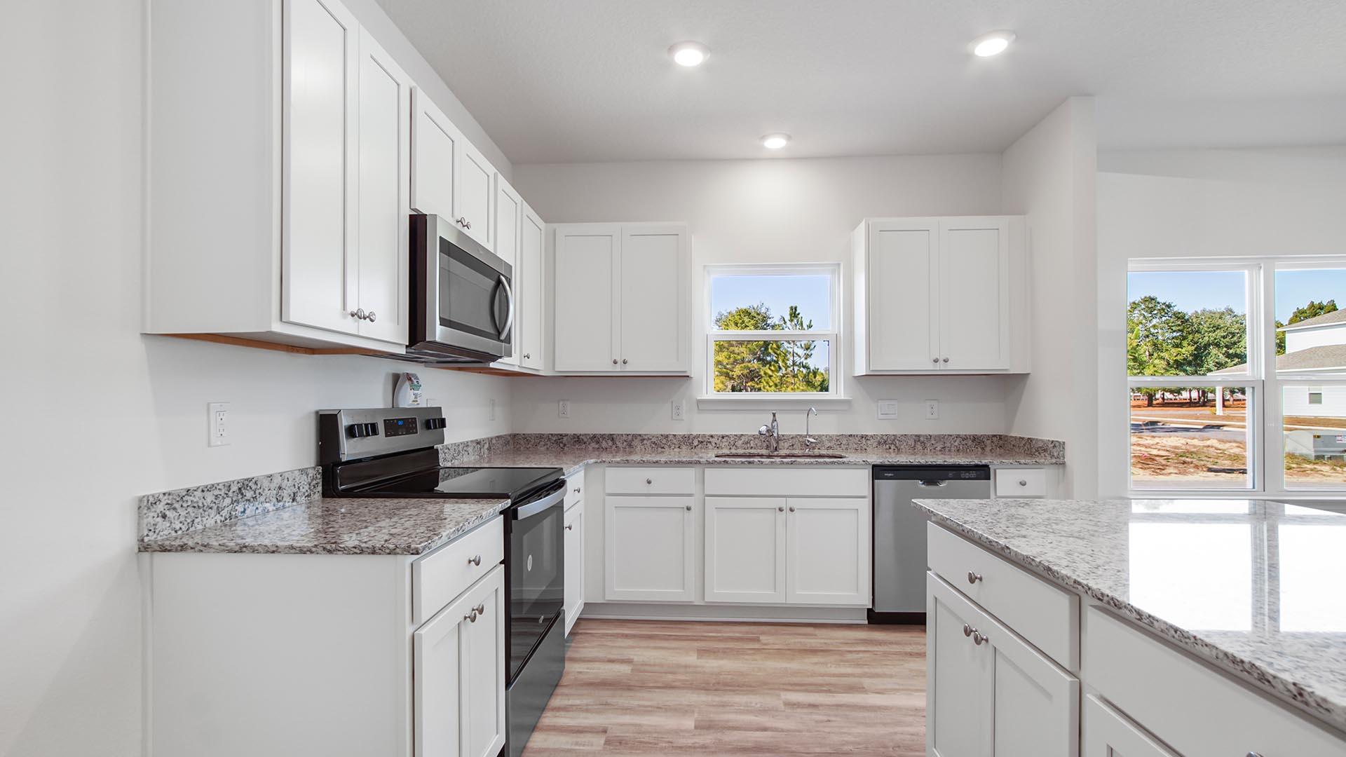 Open kitchen with beautiful white cabinetry and plenty of upper and lower cabinets for storage as well as granite countertops