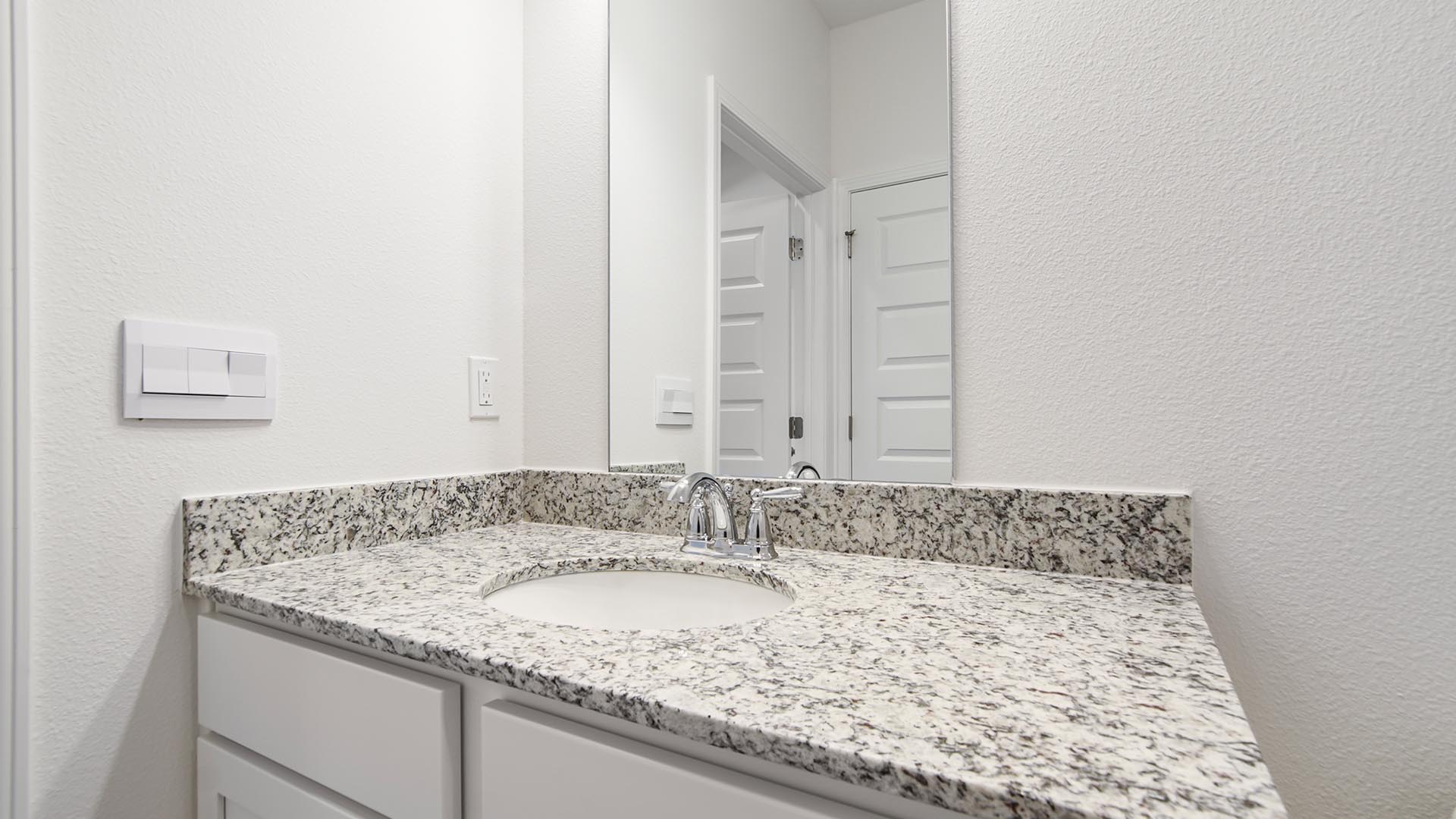 The shared bath features a single vanity with granite countertops and lower cabinetry