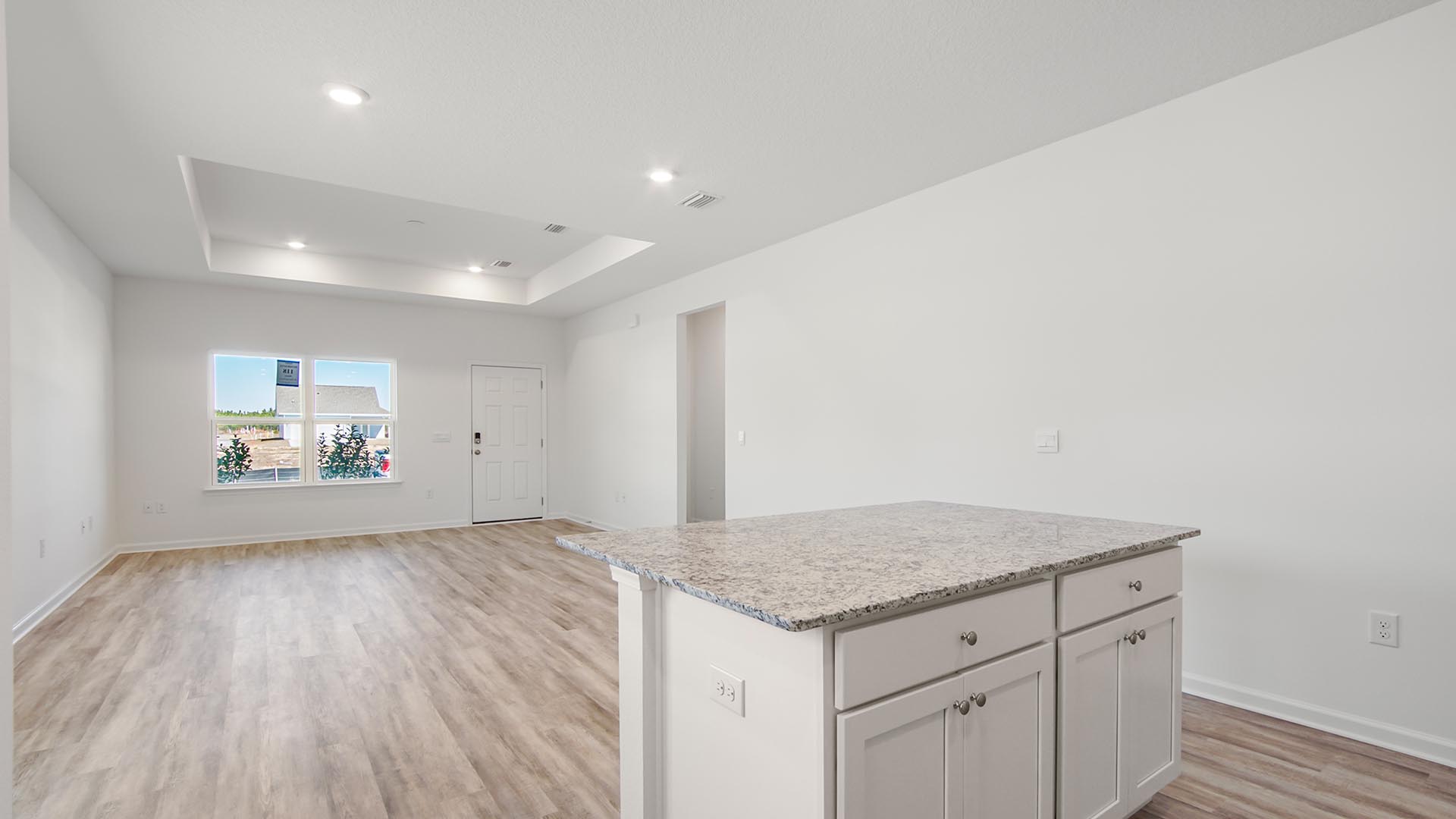 The open living area features trey ceilings   Kitchen with spacious center island featuring lower cabinetry and granite countertops