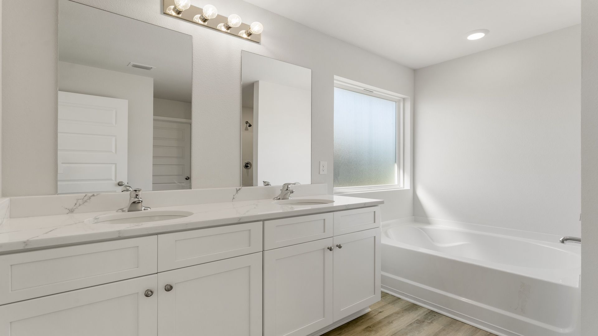 The primary bathroom has a dual sink vanity with lower cabinetry for storage and quartz countertops
