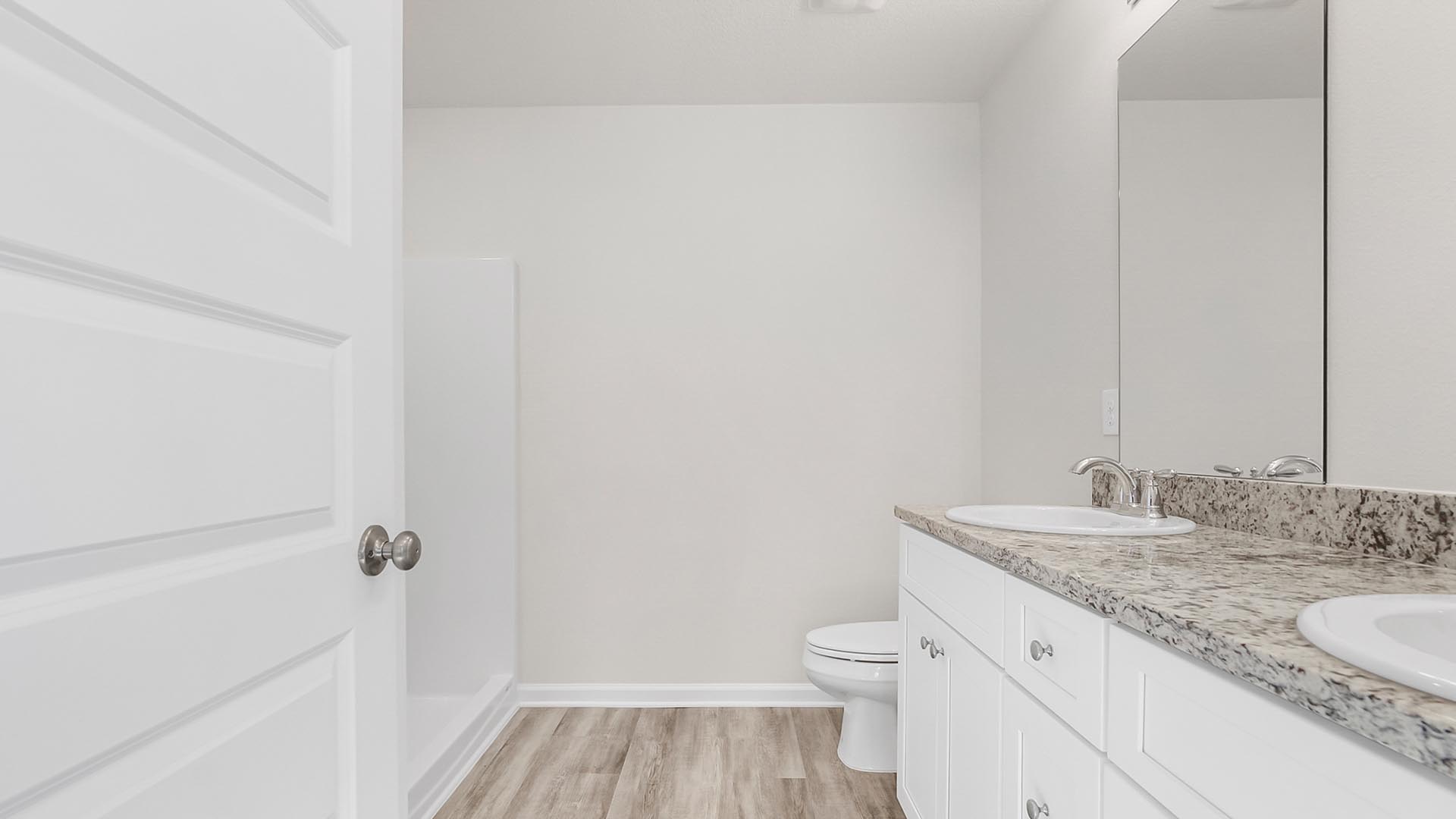 The private bath in the primary bedroom has EVP flooring and granite countertops with lower drawers and cabinetry