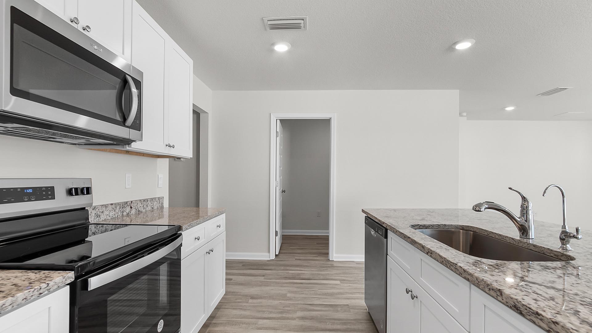 The kitchen features stainless steel appliances including a smooth top stove and microwave