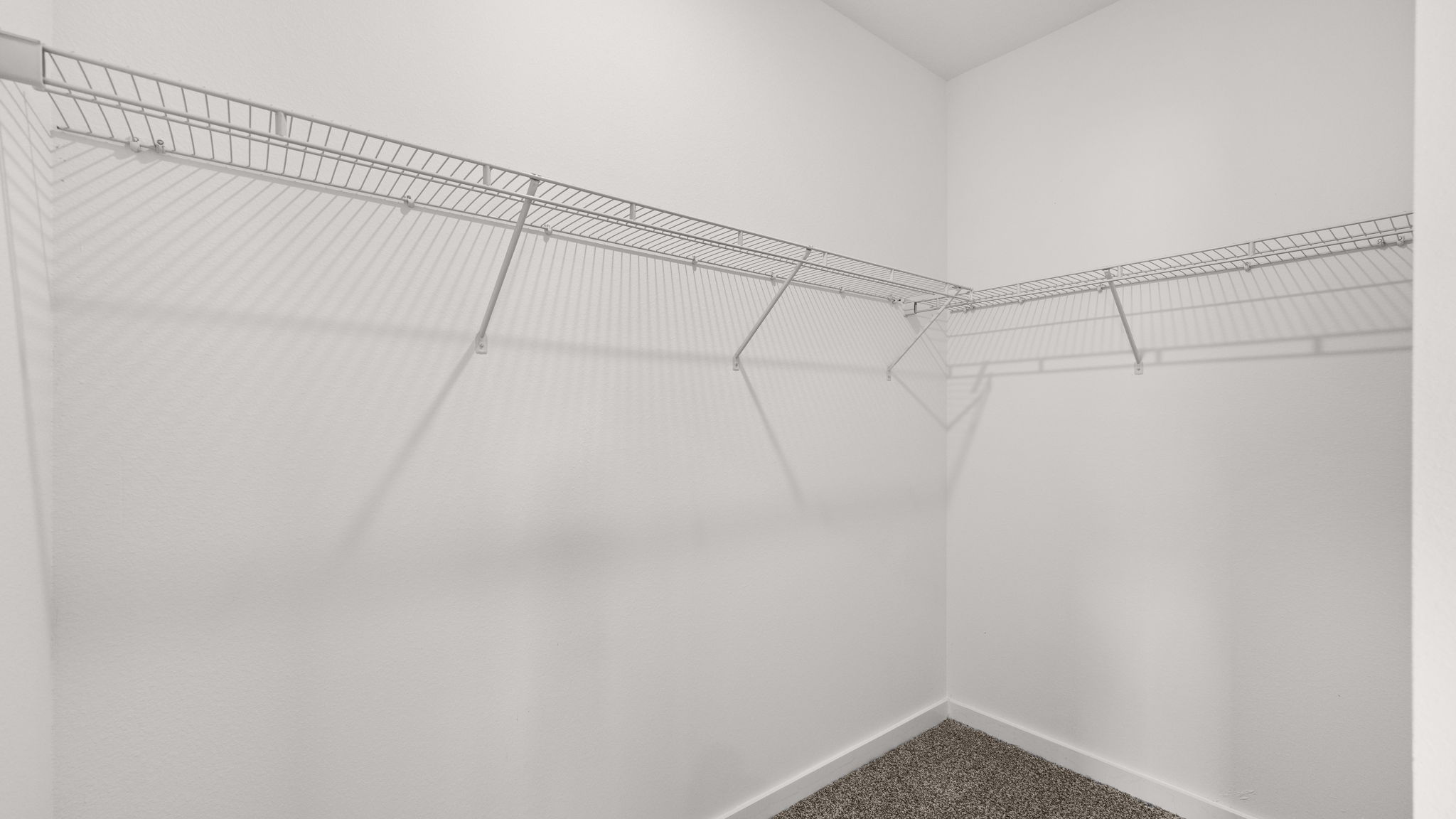 The walk-in closet has upper ventilated shelving