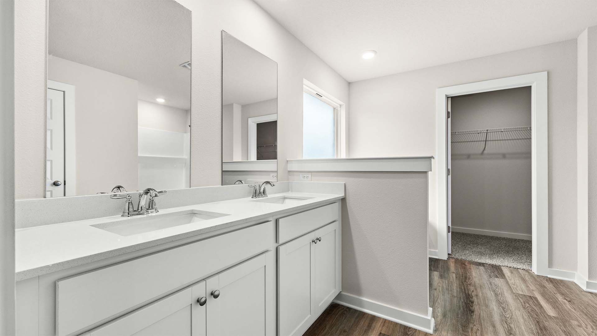 Primary bathroom with quartz counters and lower cabinetry for storage
