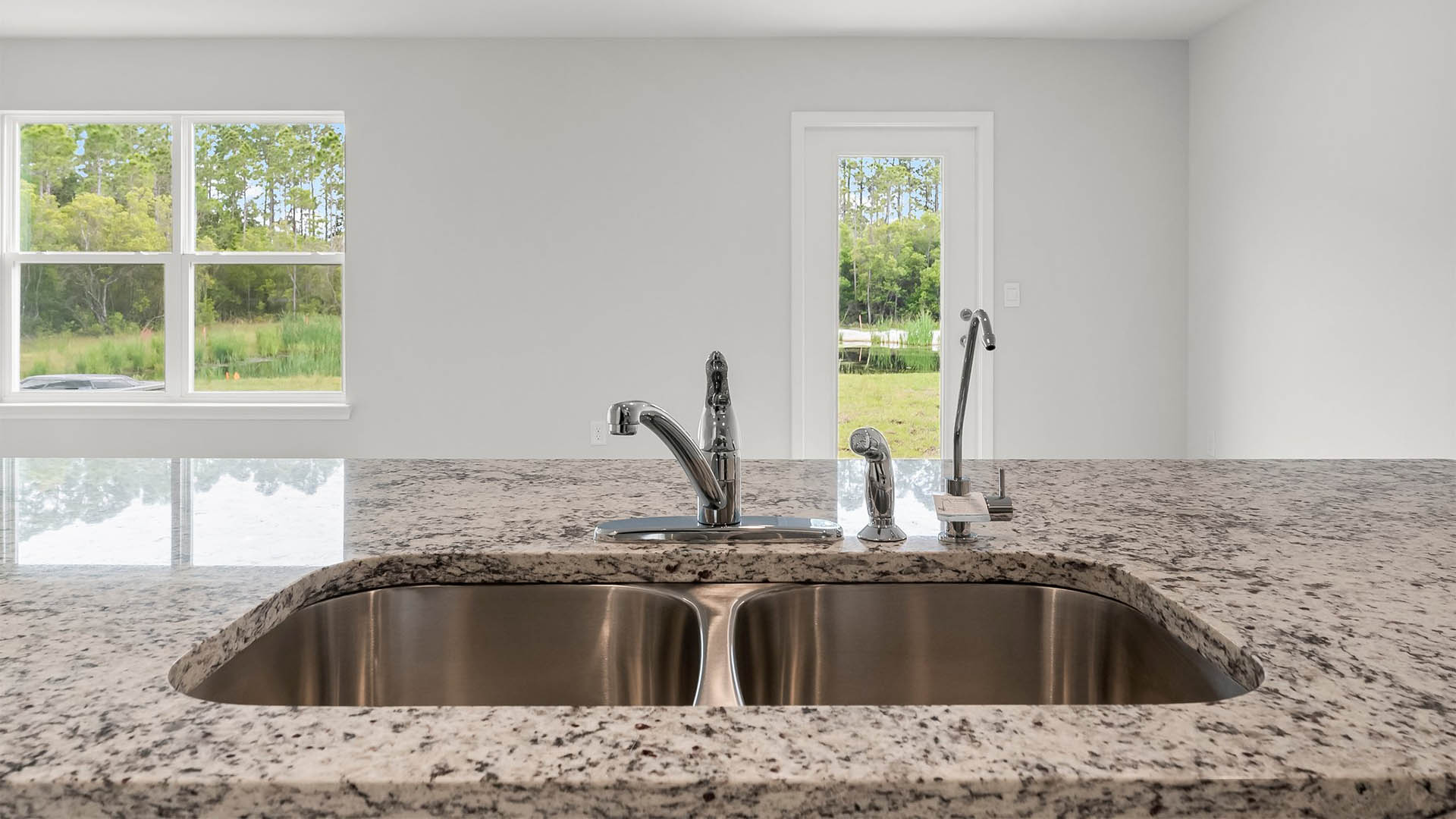 The kitchen island features granite countertops and stainless sink basin and dishwasher