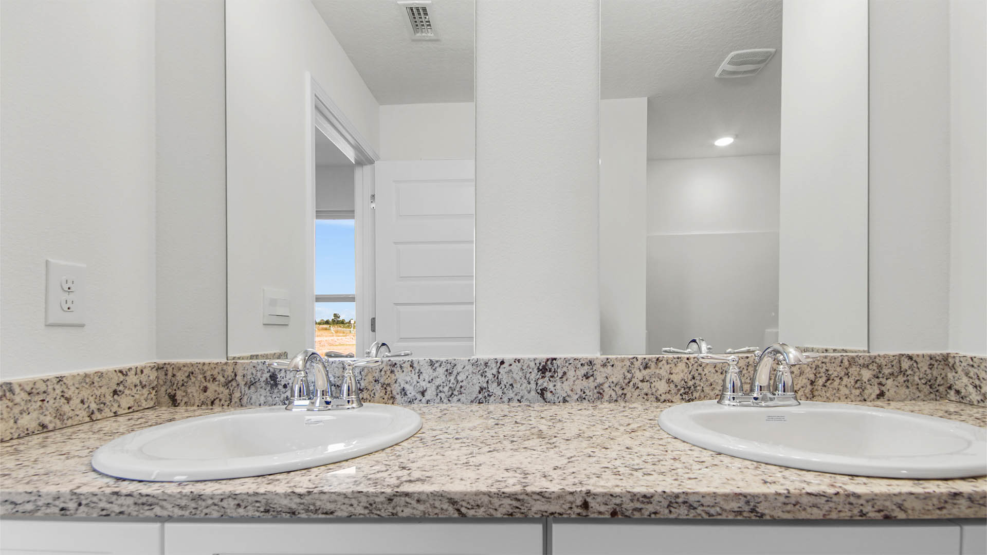 The dual sink vanity in the primary has granite countertops and lower cabinetry