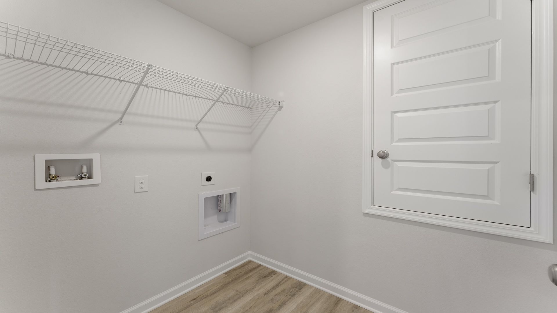A nice size laundry room with hookups for washer and dryer and an upper shelf