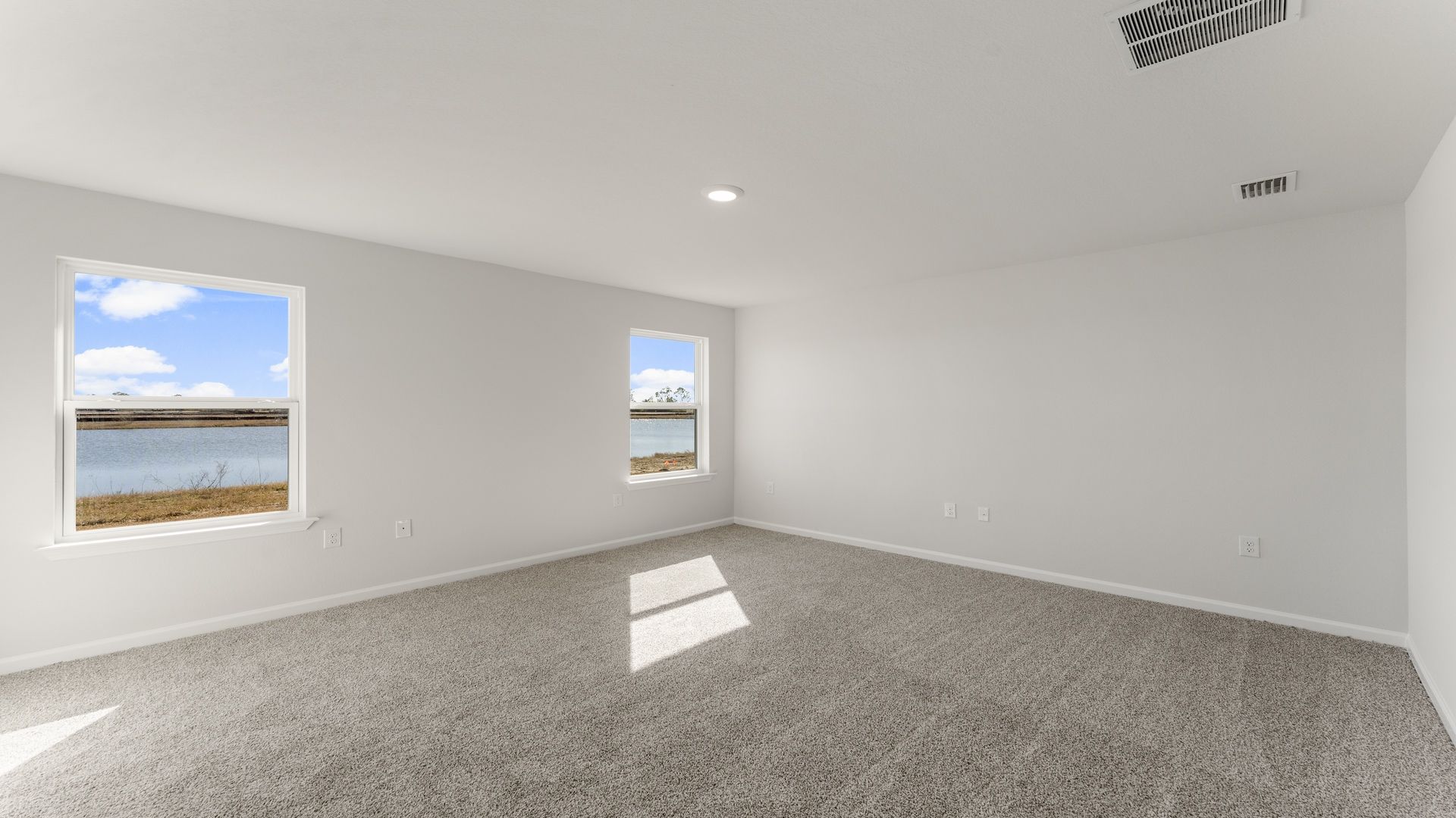 The primary bedroom has large windows allowing for natural light