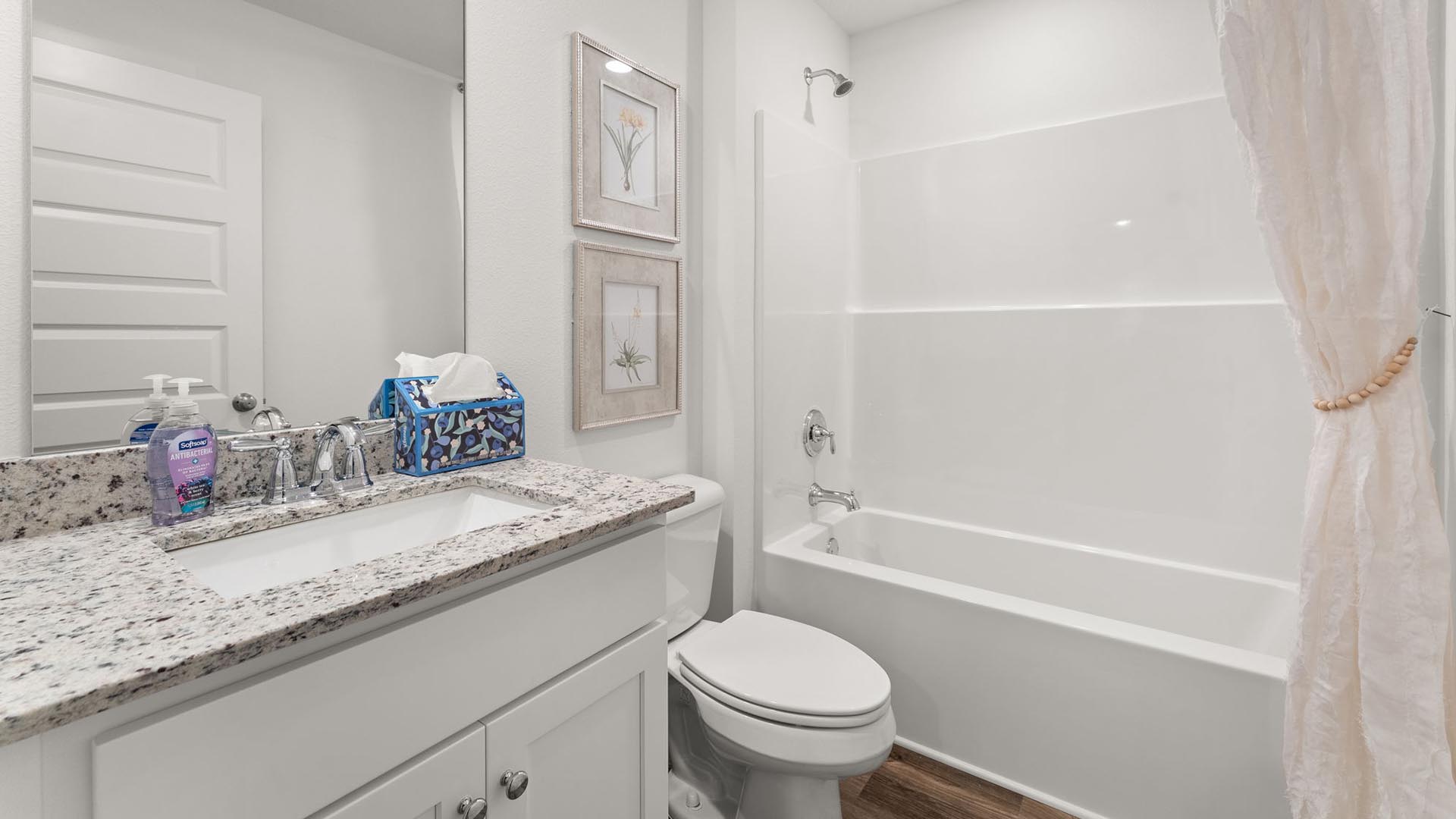 There is a shared bathroom between bedrooms two and three with a shower tub combination and a single vanity with lower cabinetry for storage