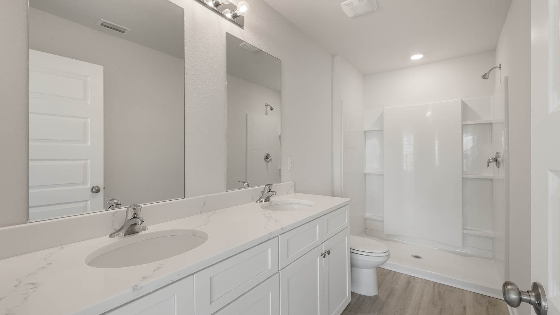 The primary bath has a dual sink vanity with quartz countertops and lower cabinetry and drawers for storage