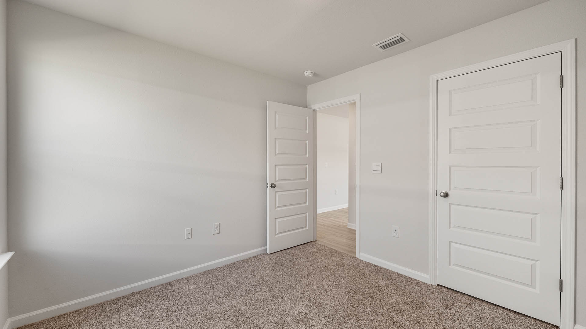Guest bedroom one has carpet and a spacious closet