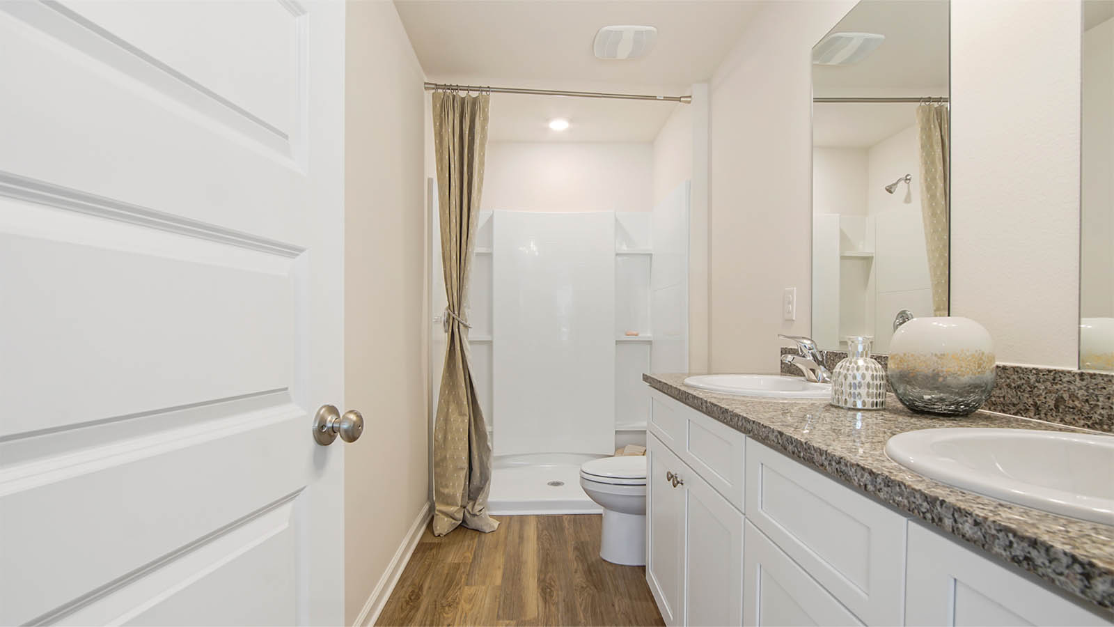 The primary bathroom has a dual sink vanity with lower cabinetry and granite countertops