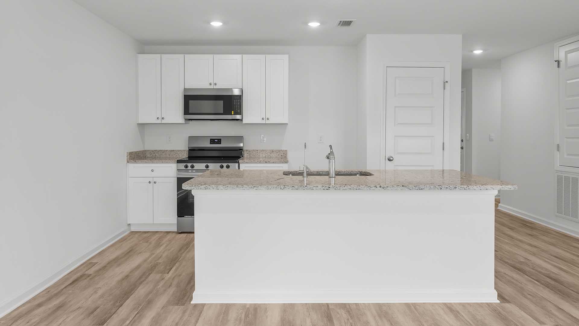 The kitchen island has quartz countertops. This image shows granite countertops