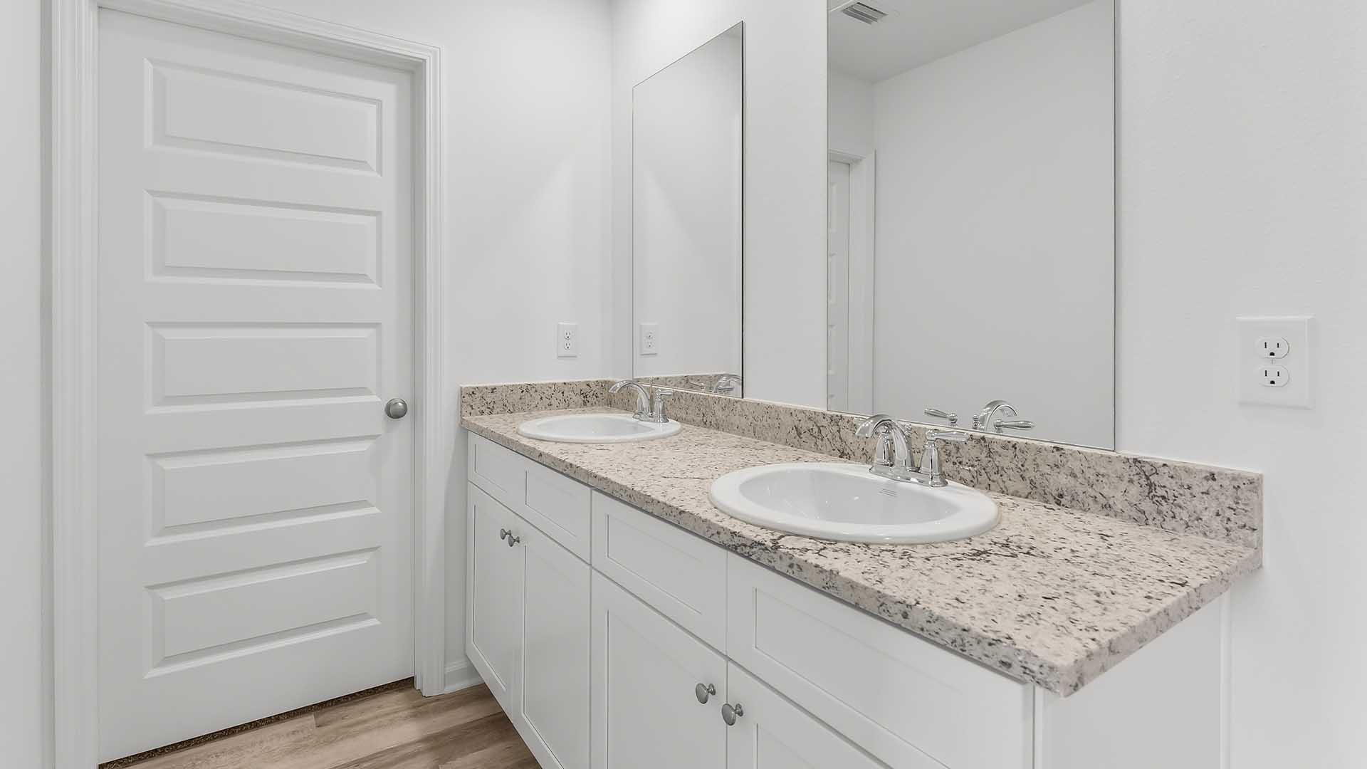 The primary bathroom has a dual sink vanity with lower cabinetry