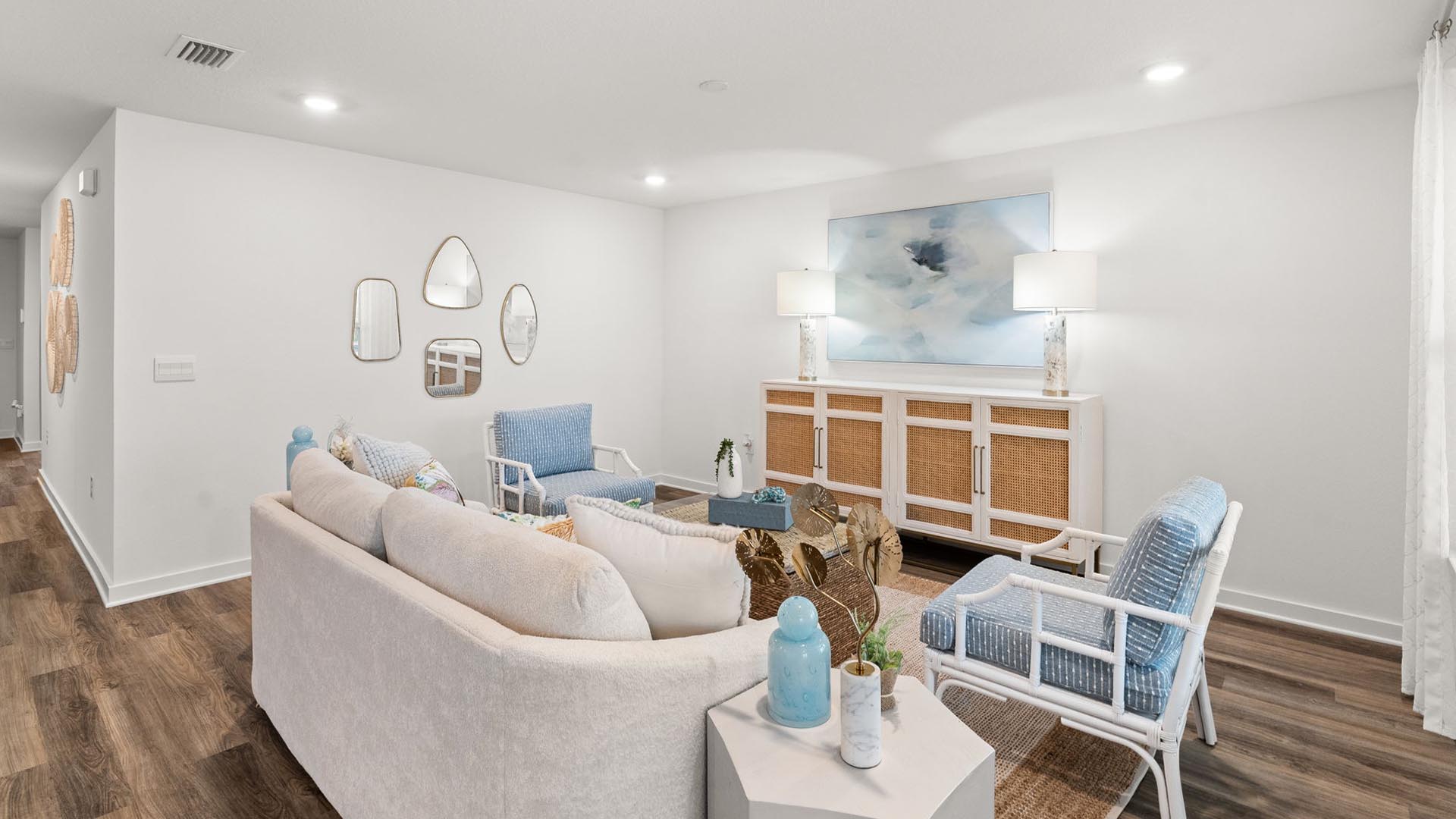 This image shows the living area with couch two chairs and a credenza or entertainment center. This is the staged model home of the Aria floor plan