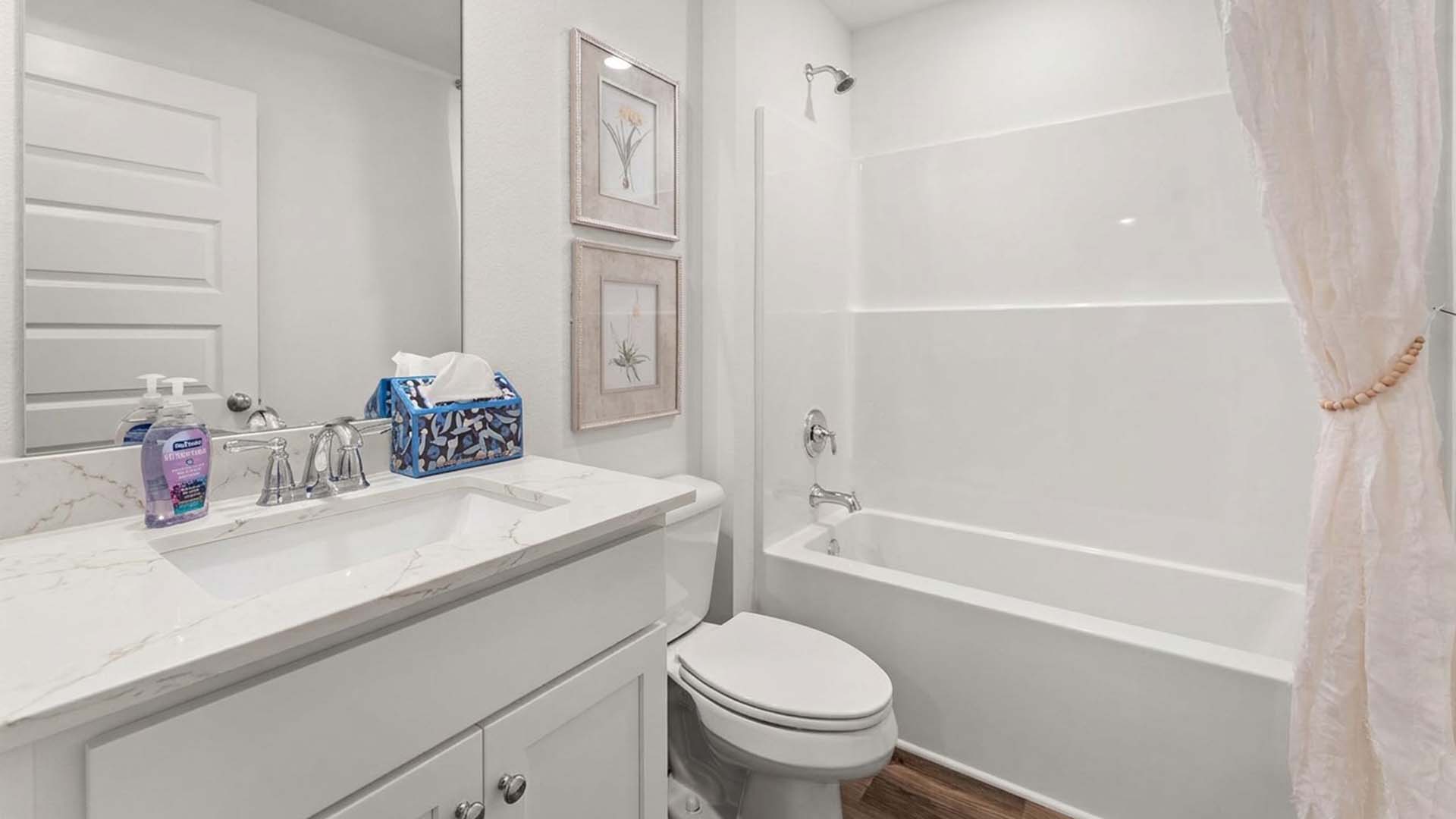 There is a shared bathroom between bedrooms two and three with a shower tub combination and a single vanity with lower cabinetry for storage