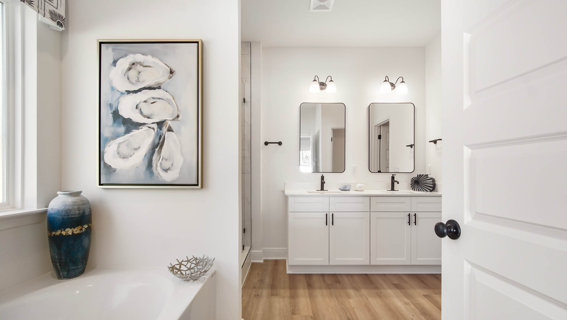 Primary bathroom is elegantly appointed with EVP flooring quartz countertops and a dual sink vanity with single mirror over each sink