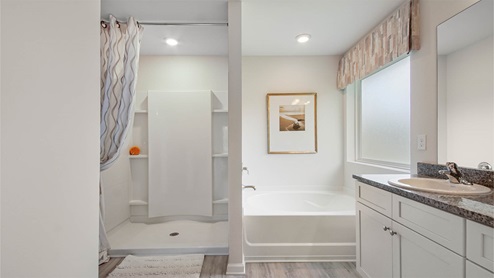 Primary bathroom features a dual sink vanity with granite countertops and lower cabinetry