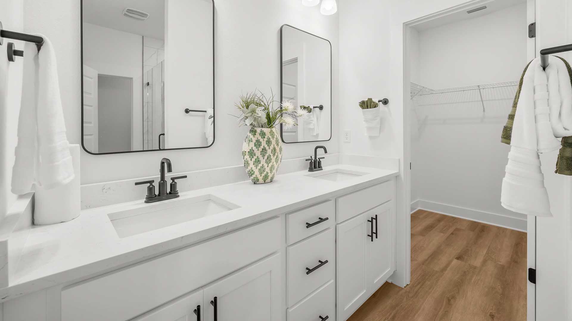 The vanity has lower cabinetry for storage and there is a shower with glass door