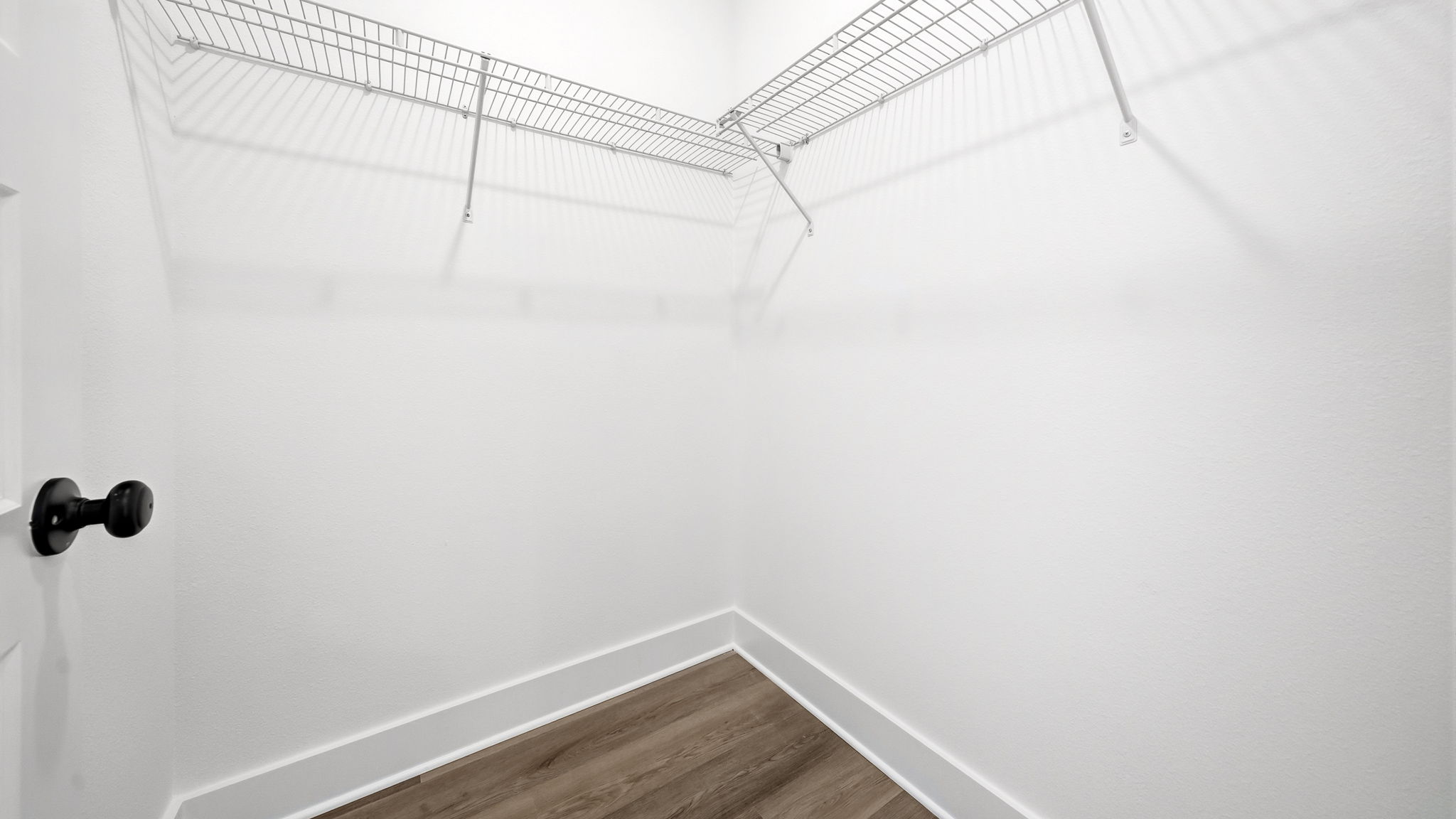 The spacious closet in the primary bedroom has overhead ventilated shelving