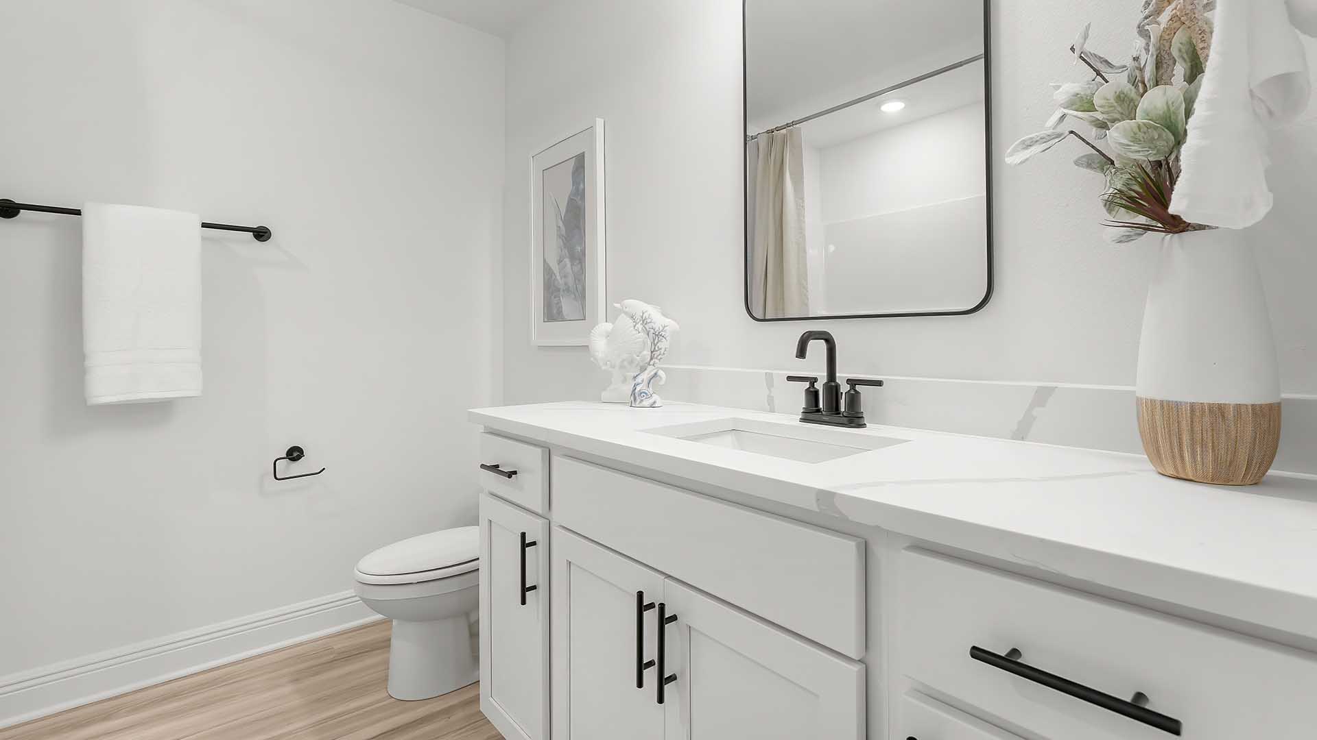 The shared bathroom has quartz countertops with a dual sink vanity and lower cabinetry for storage. There is a shower tub combination