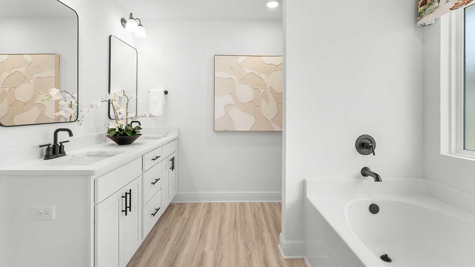 The primary bathroom has beautiful features including quartz countertops, EVP flooring, a tile shower with glass enclosure and beautiful white cabinetry