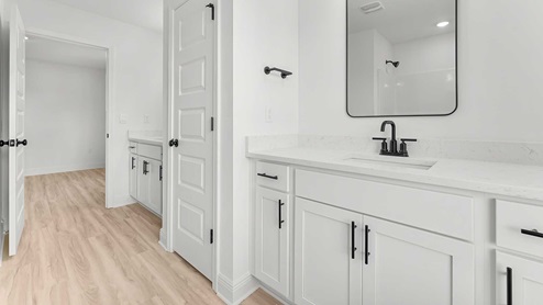 The adjoining bathroom has separate vanities with a linen storage area between