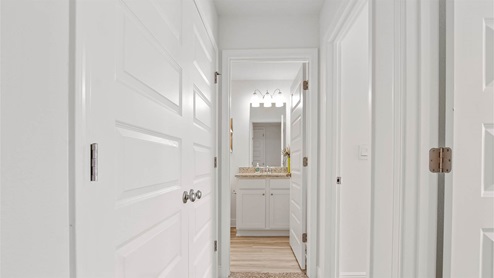 Hall leading to shared bathroom outside of additional bedrooms