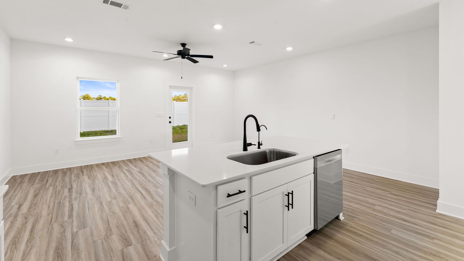The kitchen has matte black plumbing fixtures and the island holds a sink and dishwasher