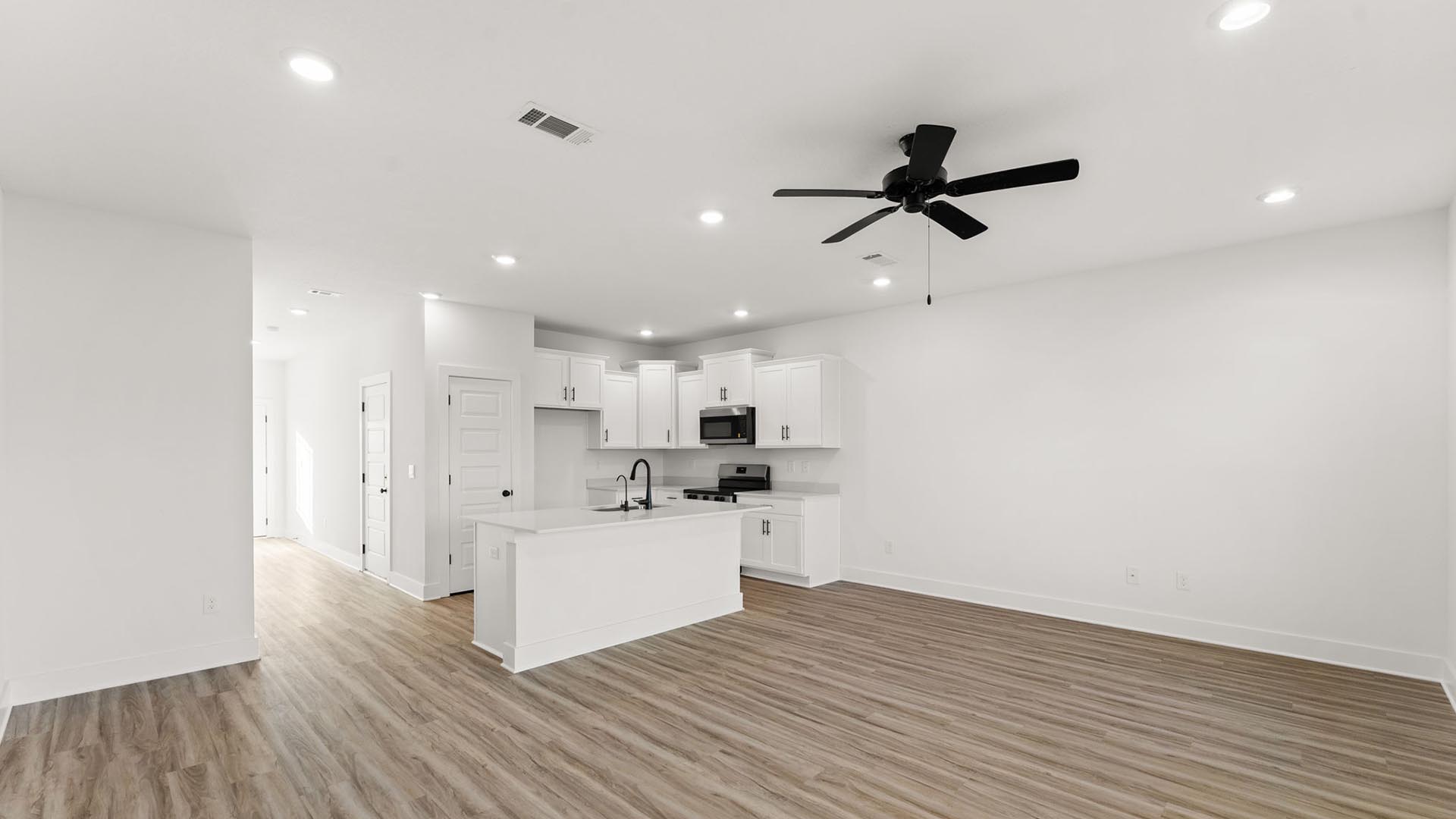 The living area has a ceiling fan and is well lit by windows which allow for natural light