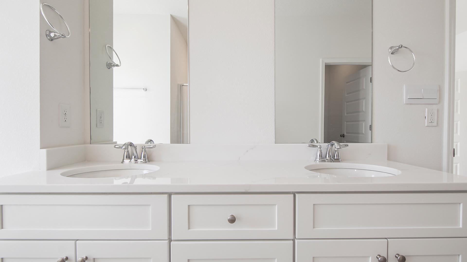 The primary bathroom has a dual sink vanity with lower cabinetry and quartz countertop