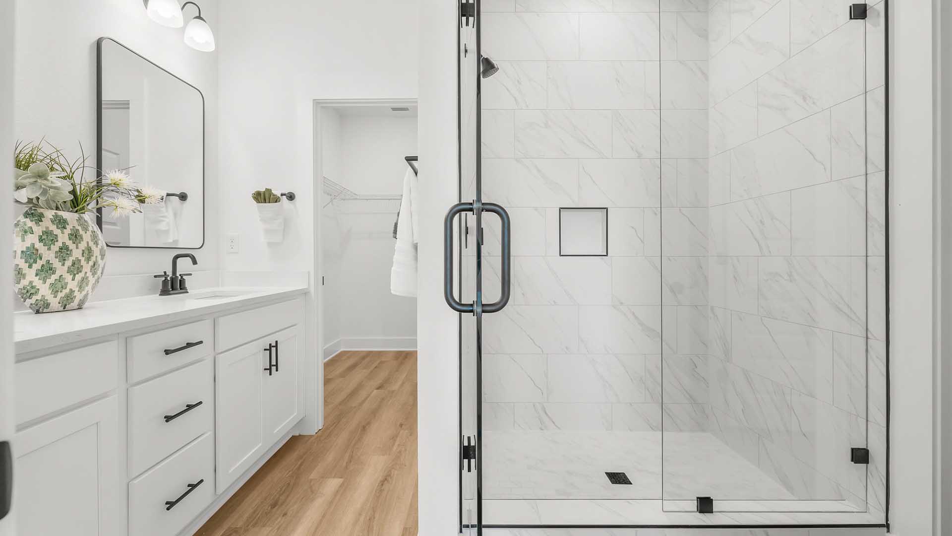 The bathrooms have quartz countertops, black plumbing fixtures and tile shower with glass enclosure