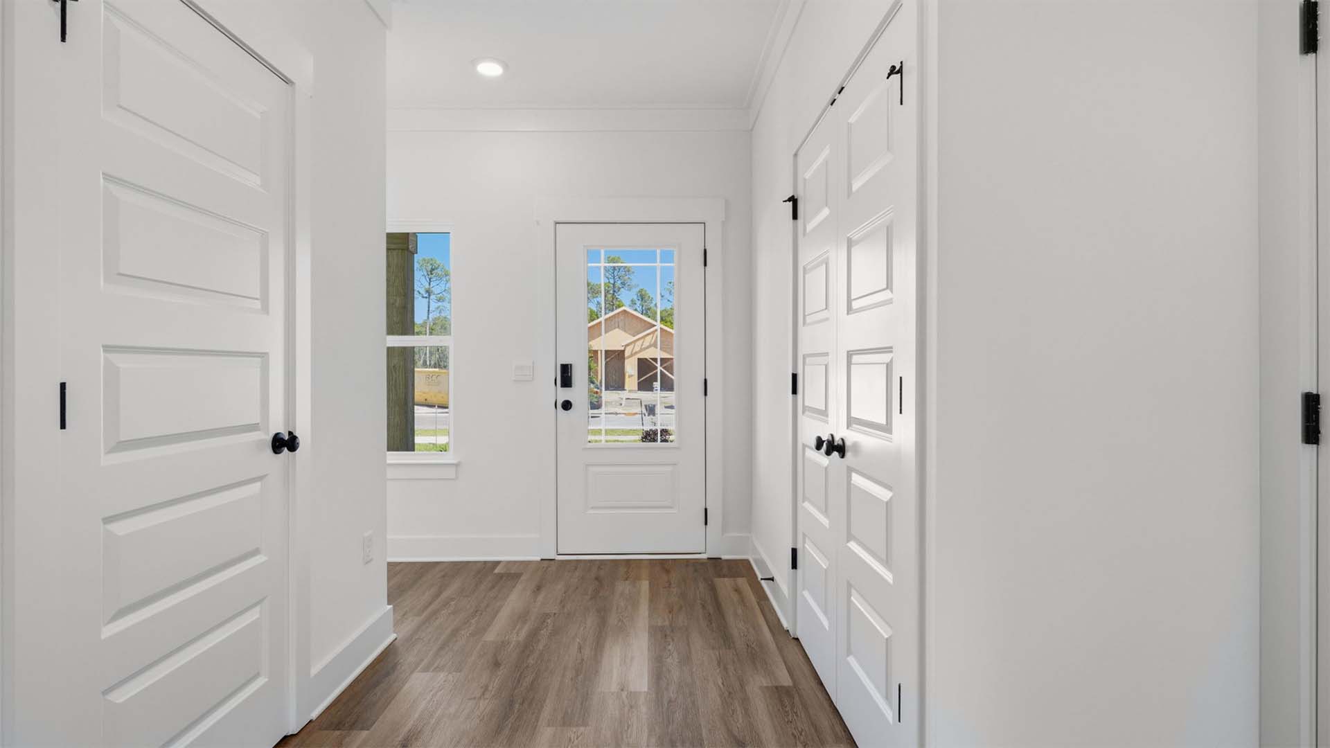 Bright entry of the Monroe floor plan features a hall with EVP flooring and prairie style glass front door