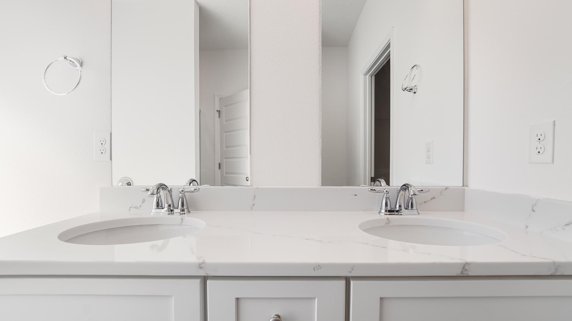 Primary bathroom with a double vanity with quartz countertops and white cabinetry.