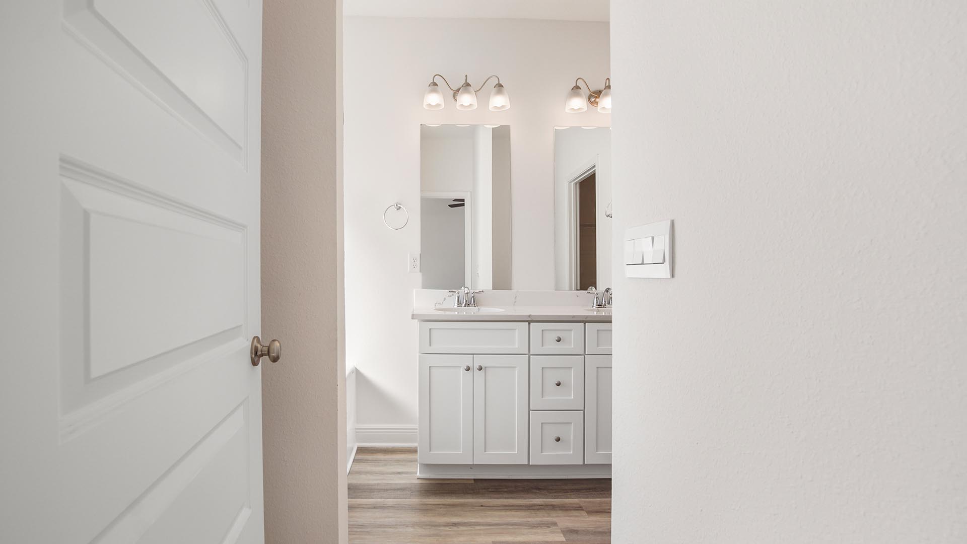 Primary bathroom with double vanity and large soaking tub below frosted glass window and separate standing shower.