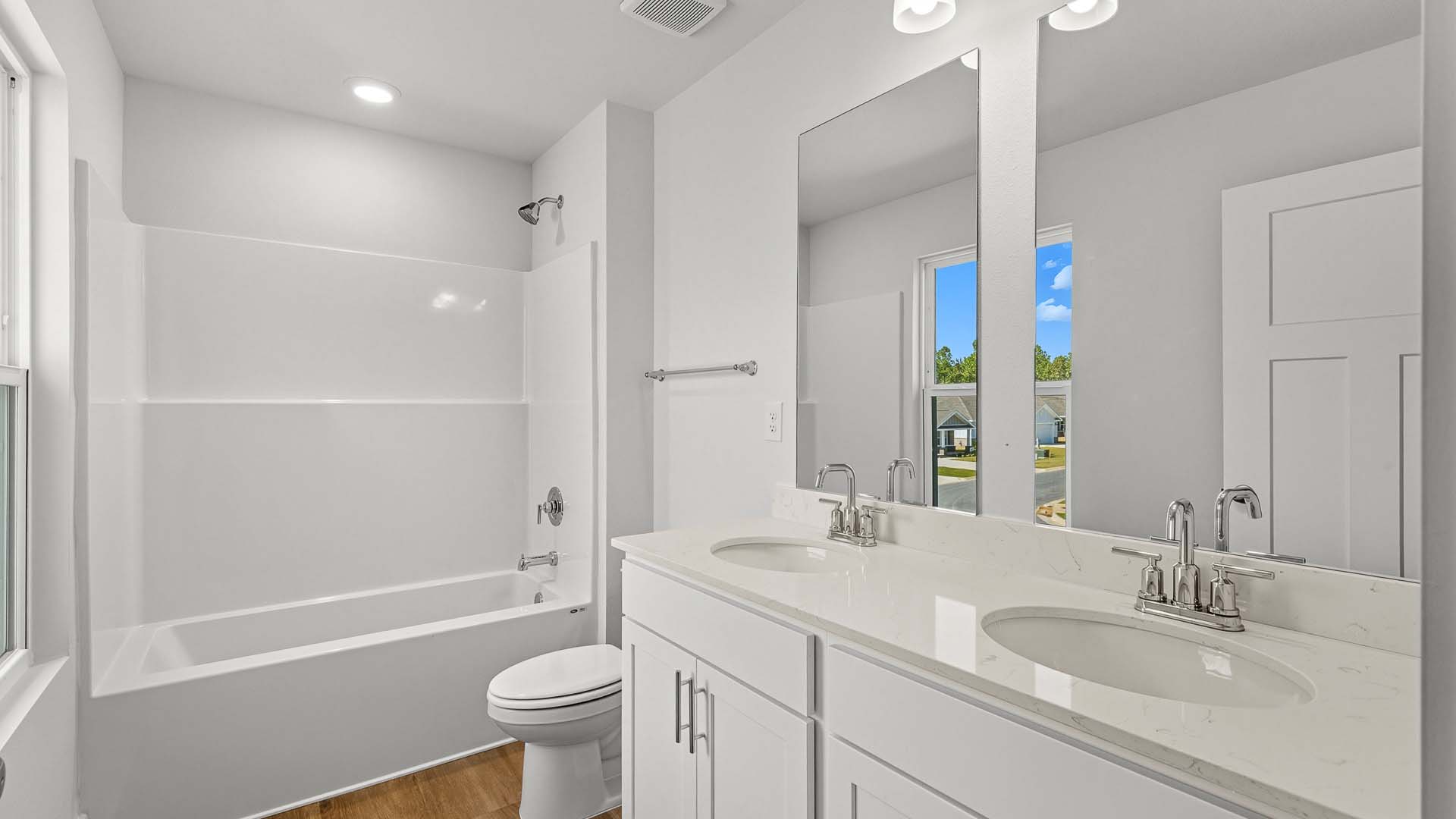 There is a shared bathroom with a shower tub combination and dual sink vanity and lower cabinetry for storage