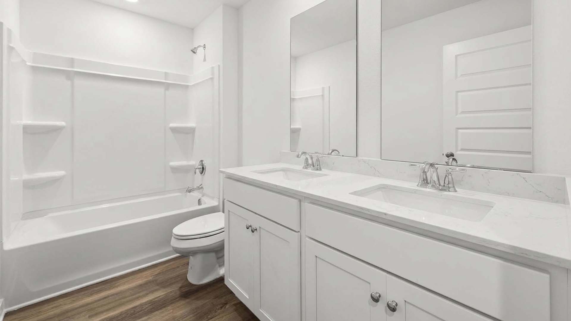 There is a shared bathroom with shower tub combination and quartz countertops and dual sink vanity